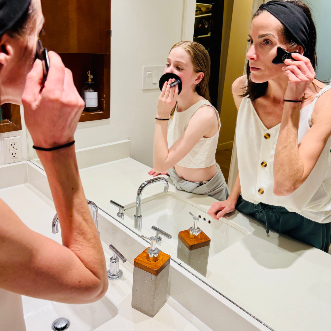 Generational skincare Mother and daughter using Chinook skincare superfruit gel to milk cleanser in the bathroom and applying to their faces in front of a mirror with sink