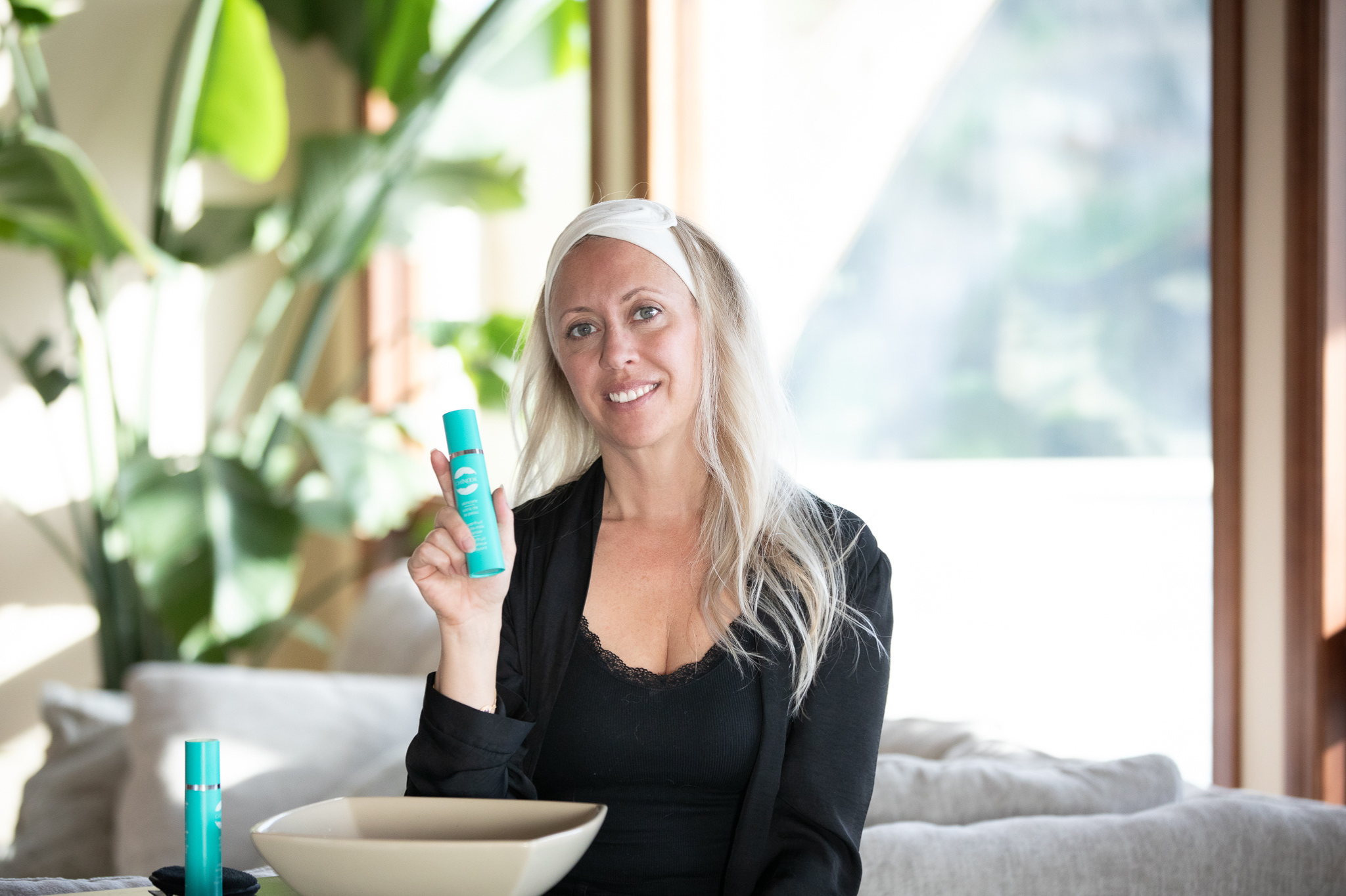 Megan Houde holding and promoting Superfruit Gel-to-Milk Cleanser and Elderberry Serum Cream Bottles - Chinook Skincare
